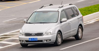 Silver minivan front and side view with roof rails and Kia grille