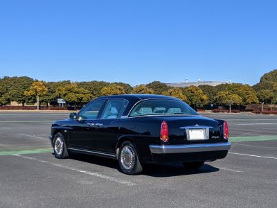 Rear side profile of a black vintage-style sedan with chrome accents and classic vertical taillights