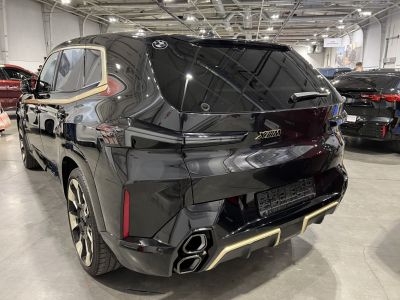 Rear view of a black SUV with gold trim and quad exhaust