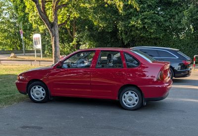 Red four-door sedan with rounded rear and simple wheels
