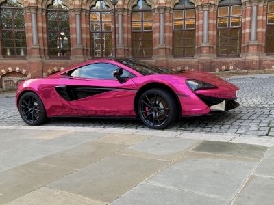 Side profile of a sleek car with pink chrome wrap and black accent details