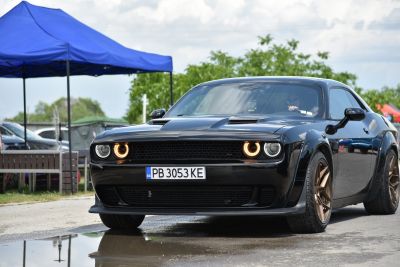 Front view of a black muscle car with halo headlights and wide wheels.