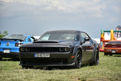 Front view of a widebody muscle car with hood scoop and aggressive headlights.