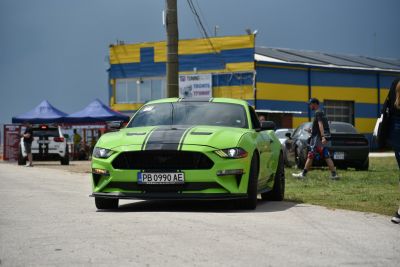 Lime green Mustang front view with black racing stripes and aggressive styling.