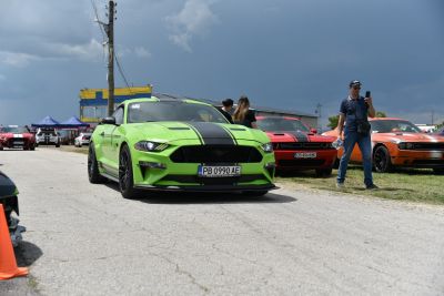 Green sports coupe with black racing stripes and black wheels