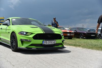 Front view of bright green sports car with black racing stripes and aggressive headlights