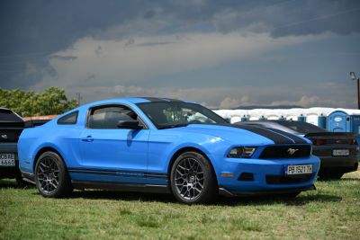 Blue muscle coupe with black racing stripes and alloy wheels