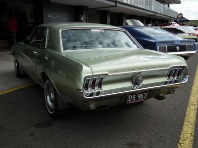 Rear view of a classic Mustang with distinctive triple vertical taillights and chrome bumper