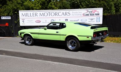 Side view of lime green muscle car with black stripes and rear spoiler