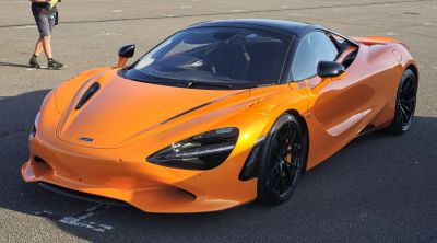 Sporty front angle of orange supercar with aerodynamic design.