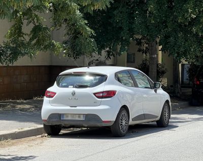 Rear and side view of a white hatchback car parked.