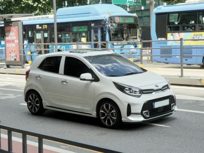 Front side view of white compact hatchback with sporty wheels and daytime running lights