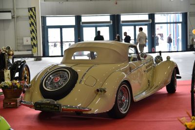 Vintage convertible with fabric soft top and rear-mounted spare wheel.