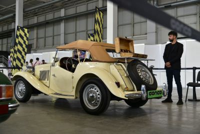 Vintage convertible with beige soft-top and rear luggage rack carrying suitcase