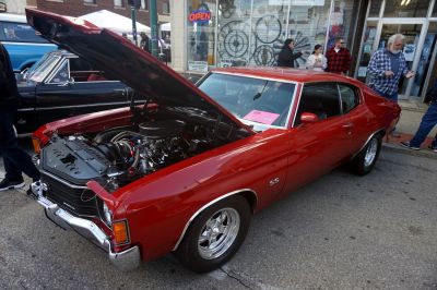 Open hood muscle coupe front side with visible engine and polished rims