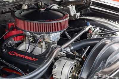 Red round air filter and Chevrolet valve covers in a detailed engine bay close-up.