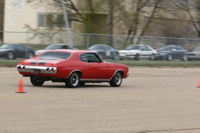 Rear view of classic red muscle coupe with racing stripes and round tail lights.