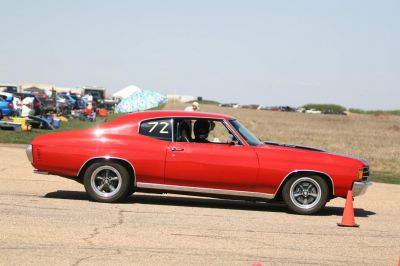 Side profile of a red classic muscle coupe with racing number 72.