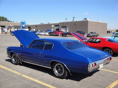 Classic blue muscle car with open hood and chrome rear.
