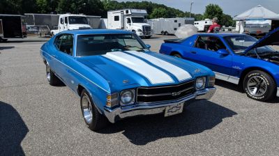 Blue muscle car front with dual white racing stripes and chrome bumper