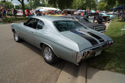 Rear and side angle of a classic muscle car with dual black racing stripes.