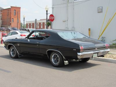 Black muscle coupe rear side view with chrome bumper and fastback roofline