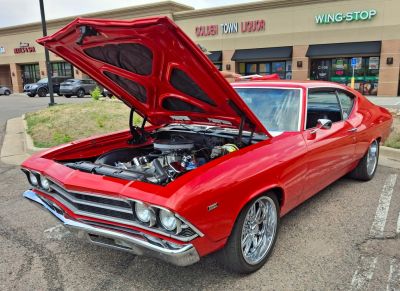Open hood showing detailed engine of a classic red muscle coupe