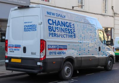 White panel van with blue business ads and pixel pattern graphics