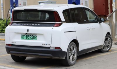 Rear view of white electric minivan with futuristic tail lights and window design