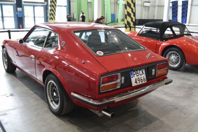 Rear side view of red vintage sports coupe with distinct taillights and 2+2 seating