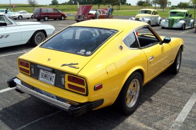 Rear side view of a yellow classic sports coupe with chrome bumper and classic taillights