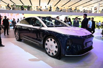 Aerodynamic electric sedan with distinct large multi-spoke wheels.
