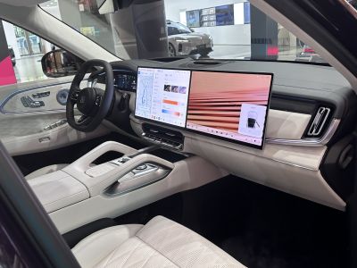 Luxury car interior featuring dual large digital displays and premium white leather seats