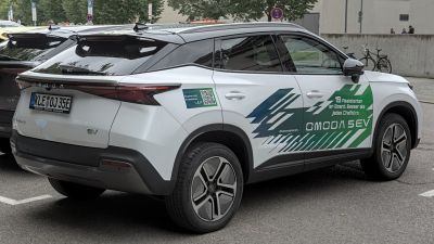 Electric SUV rear and side, aerodynamic spoiler, modern alloy wheels.