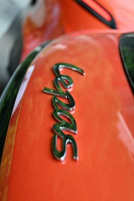 Close-up of metallic rear badge on orange car body
