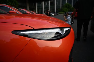 Close-up of angular LED headlight on glossy orange vehicle