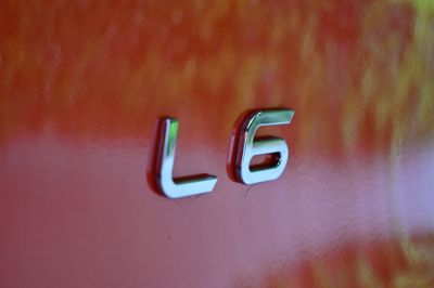 Close-up of chrome L6 badge on orange car surface