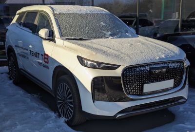 Front view of a snow-covered SUV with distinctive grille and stylish rims