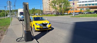 Yellow electric taxi charging at public roadside station