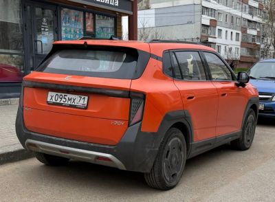 Rear view of orange modern electric SUV with unique taillight design and black trim