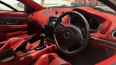 Red leather car interior with black steering wheel and manual gear shift