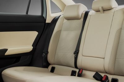 Beige perforated leather rear seats with black seatbelts and integrated headrests