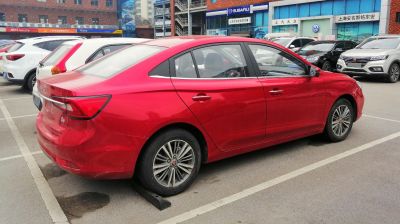 Red sedan side profile featuring rear lights and alloy wheels