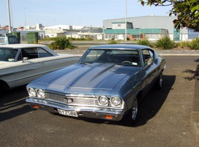Dual headlights and pronounced hood scoop on a vintage muscle car front.