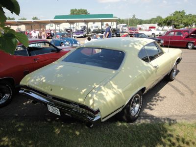 Rear view of a yellow vintage muscle coup&eacute; with SS badge and chrome bumper.