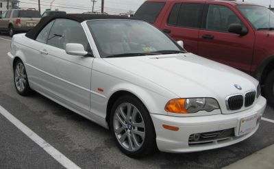 White convertible with black soft top and alloy wheels front side view