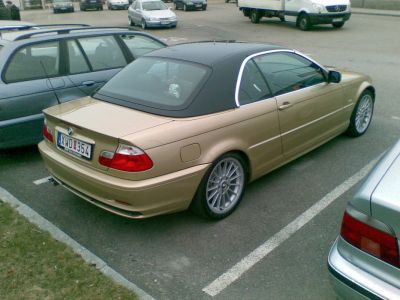 Beige convertible with soft top and alloy wheels rear view