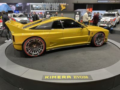 Side view of a sports coupe with large rear wing and multi-spoke alloy wheels with red-accented tires