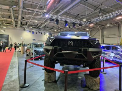 Bold front grille and massive off-road tires on raised platform.