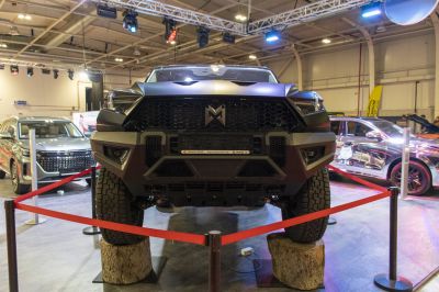 Close-up of front grill and off-road suspension with rugged tires